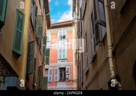 Un colorato e storico edificio di appartamenti sotto un cielo blu è visto su una strada stretta nel centro storico di Vieux Nice, Francia. Foto Stock