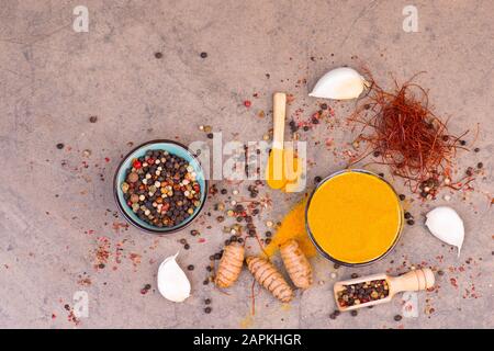 Spezie diverse, curcuma, aglio, peperoncino e pepe in un fondo di pietra testurizzata marrone, vuoto spazio copia Foto Stock