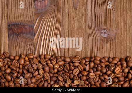 Chicchi di caffè arrosto su sfondo di legno. Vista dall'alto. Spazio di copia. Foto Stock