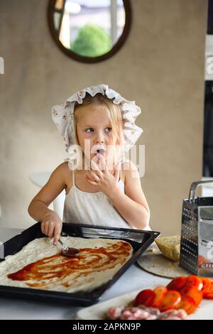 Bambina che cucina la pizza in cucina Foto Stock