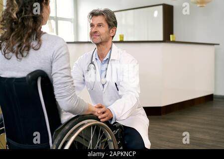 Medico che si prende cura della paziente in sedia a rotelle Foto Stock