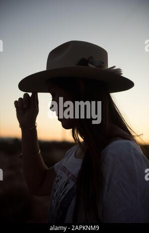 Una donna nel suo amato cappello cowboy esplorare il tramonto in Joshua Tree Foto Stock