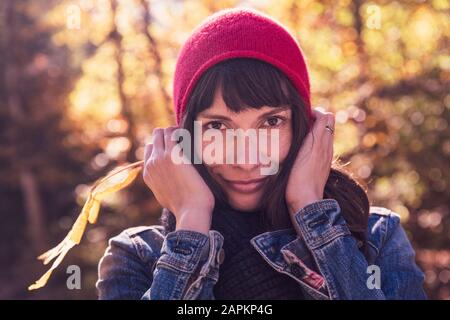 Donna che indossa cappello rosso e giacca in denim Foto Stock