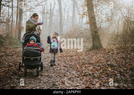 Madre con figlie durante la passeggiata nella foresta in autunno Foto Stock