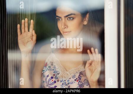 Ritratto di giovane donna guardando fuori della finestra Foto Stock