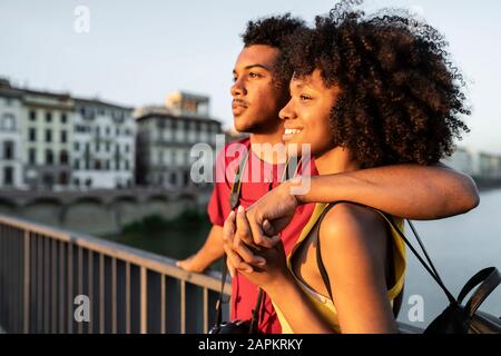 Felice giovane coppia turistica su un ponte sopra l'Arno al tramonto, Firenze, Italia Foto Stock