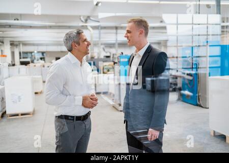 Due imprenditori parlando in una fabbrica Foto Stock