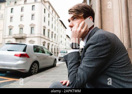 Giovane uomo d'affari con smartwatch al telefono in città Foto Stock