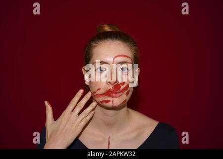 Ritratto di giovane donna che spalma vernice sul suo viso Foto Stock