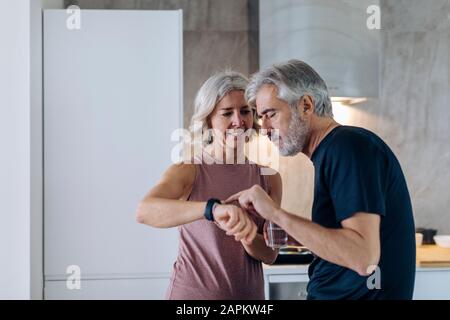Coppia matura che usa lo smartwatch in cucina a casa Foto Stock
