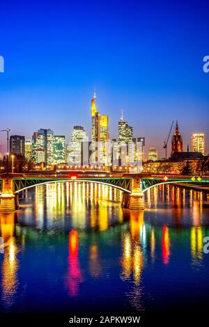 Germania, Assia, Francoforte, skyline della città attraverso il fiume meno al crepuscolo Foto Stock