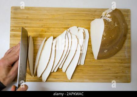 Mano dell'uomo che taglia la betulla polypore su tavola di legno Foto Stock