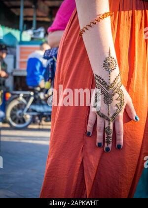 Donna in abito arancione con tatuaggio all'henné La sua mano in Marocco Foto Stock