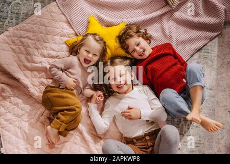 Tre ragazze felici sdraiate sulle coperte a casa Foto Stock