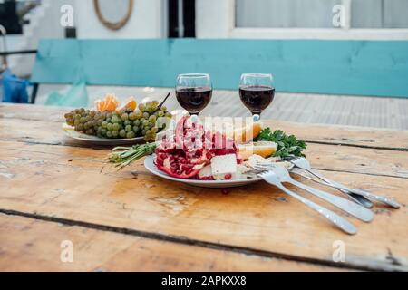 Georgia, Tbilisi, frutta fresca e bicchieri di vino rosso su tavola di legno all'aperto Foto Stock