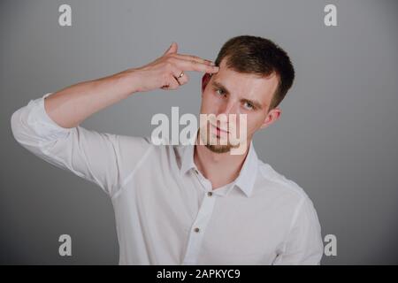 Ritratto di giovane uomo del dito puntato gesto di pistola alla testa Foto Stock