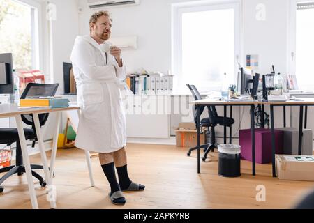 Uomo d'affari con accappatoio in una tazza da ufficio Foto Stock