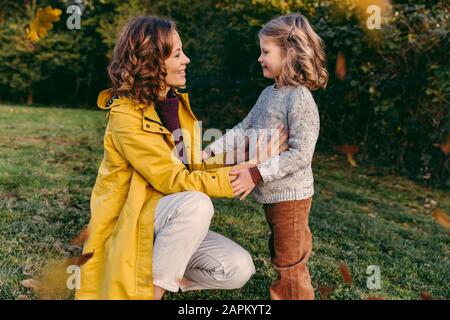 Madre sorridente con figlia su un prato in autunno Foto Stock