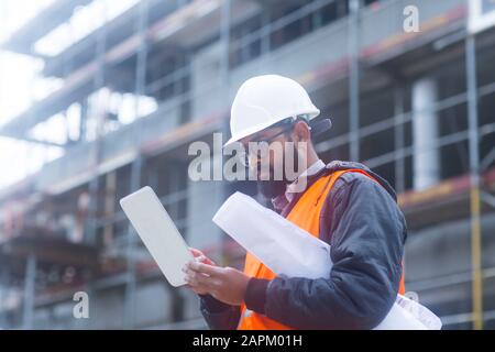 Ingegnere edile che indossa un cappello duro e un giubbotto di sicurezza per la creazione di un tablet presso il cantiere Foto Stock