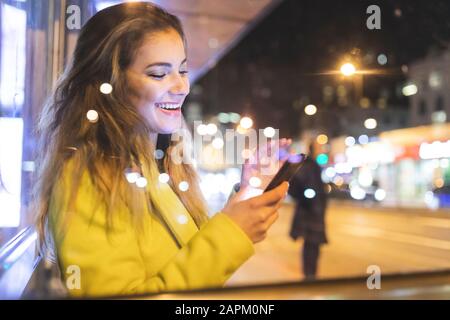 Donna felice in attesa dell'autobus in città di notte, Londra, Gran Bretagna Foto Stock