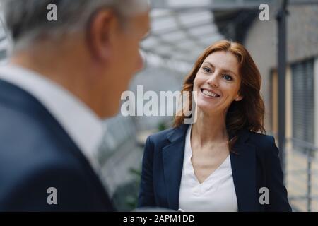 Ritratto di donna d'affari sorridente che parla con l'uomo d'affari in ufficio Foto Stock