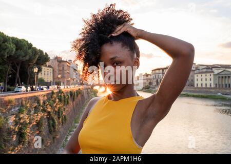 Ritratto di una giovane donna sicura sul fiume Arno al tramonto, Firenze, Italia Foto Stock