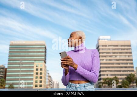 Ritratto di donna dai capelli bianchi con smartphone in città Foto Stock