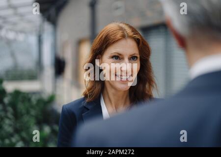 Ritratto di donna d'affari sorridente che parla con l'uomo d'affari in ufficio Foto Stock