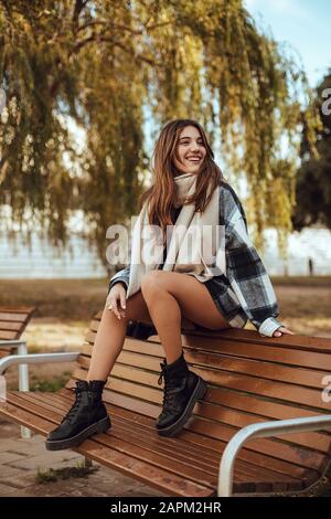 Giovane donna bruna con cappotto e sciarpa bianchi e neri in città Foto Stock