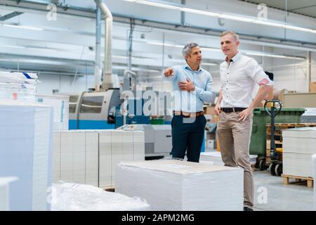 Due colleghi che parlano in fabbrica Foto Stock