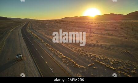 Jeep guida su una pista sporca nel deserto del Namib con sole nascosto dietro le dune, Namibia Foto Stock