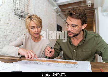Due architetti lavorano insieme alla scrivania in ufficio Foto Stock