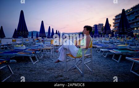 Donna matura che riallaccia sulla spiaggia al tramonto, San Bartolomeo al Mare, Italia Foto Stock