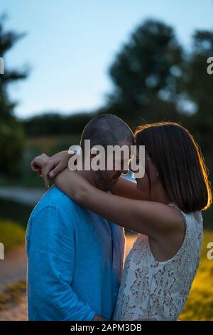 Coppia in amore abbracciando all'aperto al tramonto Foto Stock