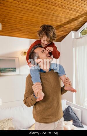 Buon padre che porta figlia sulle spalle a casa Foto Stock