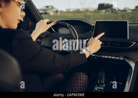 Giovane donna che usa il dispositivo di navigazione in auto Foto Stock