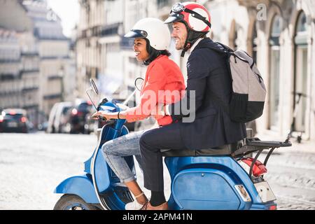 Felice giovane business coppia moto scooter in città, Lisbona, Portogallo Foto Stock