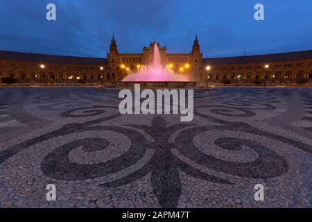 Spagna, Siviglia, Plaza de Espana, Fontana ed edifici illuminati al tramonto Foto Stock