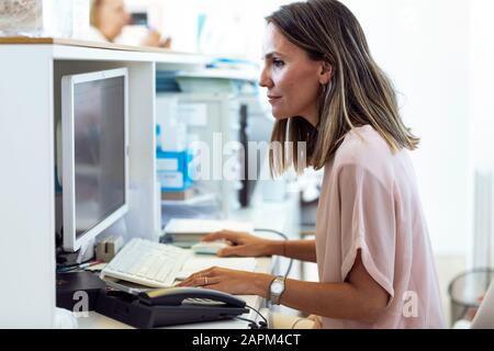 Donna che lavora al computer alla reception Foto Stock