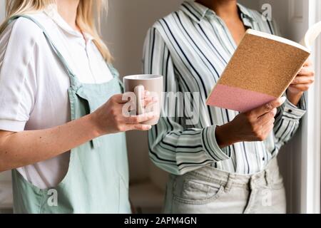 Vista dal taglio corto di due donne con taccuino e tazza di caffè Foto Stock
