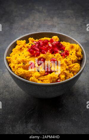 Ciotola di hummus di zucca con semi di sesamo nero e melograno Foto Stock