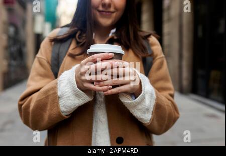 Primo piano di giovane donna con caffè da asporto in città, Barcellona, Spagna Foto Stock