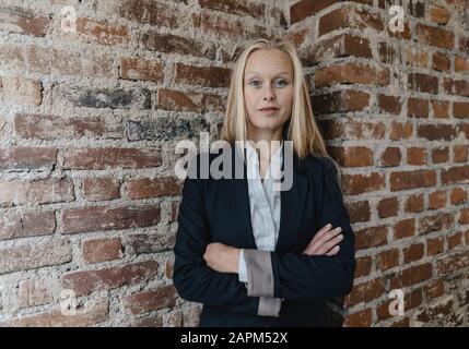 Ritratto di una giovane donna d'affari sicura ad un muro di mattoni Foto Stock