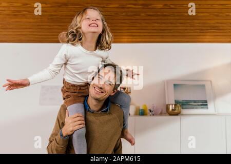 Buon padre che porta figlia sulle spalle a casa Foto Stock