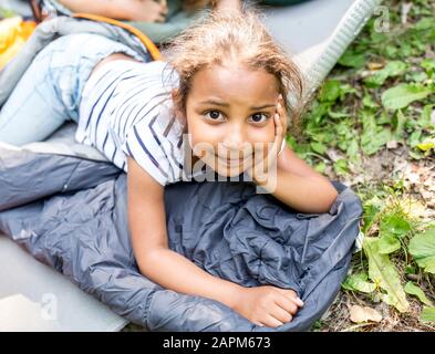 Bambina sdraiata sul sacco a pelo, guardando la macchina fotografica Foto Stock