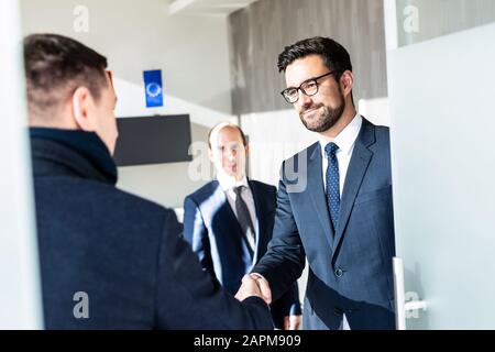 Gruppo di fiduciosi uomini d'affari salutano con una stretta di mano durante la riunione d'affari in ufficio moderno o chiudendo l'accordo di trattativa scuotendo le mani. Foto Stock