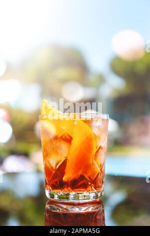 Cocktail Negroni presso il bar del resort o il patio della suite. Resort di lusso, vacanza, servizio in camera concetto. Verticale con festive bokeh luci effetto Foto Stock