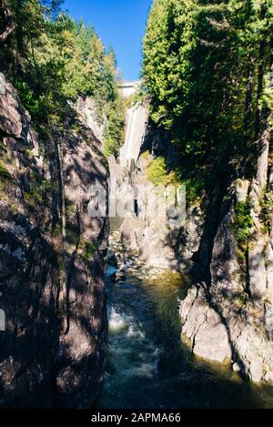 Fiume Capilano, Vancouver, Canada, attraversando una lussureggiante valle boscosa, con montagne sullo sfondo. Foto Stock