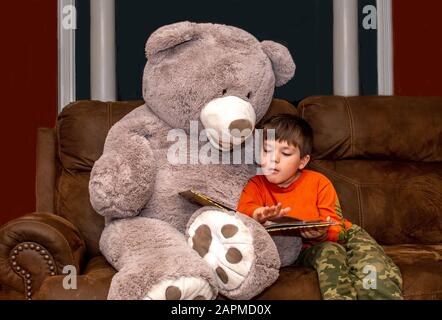 Il bambino legge un libro al suo migliore amico dell'orso Foto Stock