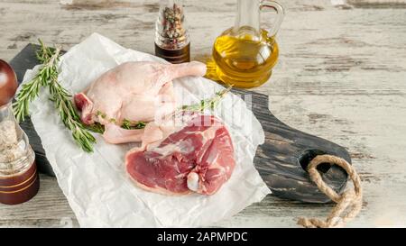 Zampe di anatra cruda. La carne di pollame è pronta per la cottura su carta e un tagliante in legno. Spazio di copia. Foto Stock